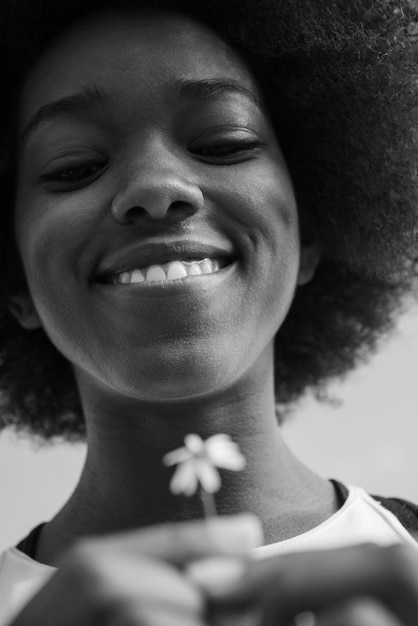 retrato de uma jovem linda garota afro-americana com uma flor de Margarida na mão