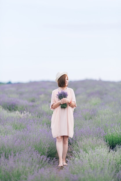 Retrato de uma jovem linda garota em um vestido rosa em um campo de lavanda