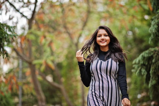 Retrato de uma jovem linda indiana ou adolescente do sul da Ásia em vestido posado no parque de outono na Europa