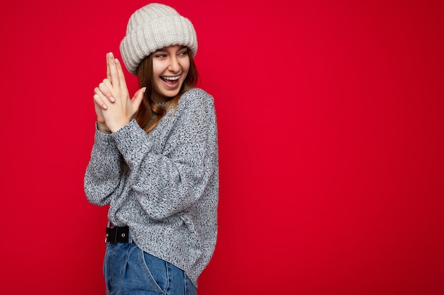 Foto retrato de uma jovem loira atraente, feliz, positiva, com emoções sinceras, vestindo roupas de cor cinza