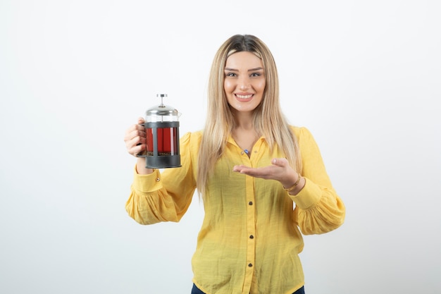 Foto retrato de uma jovem loira com bule de chá posando para a câmera