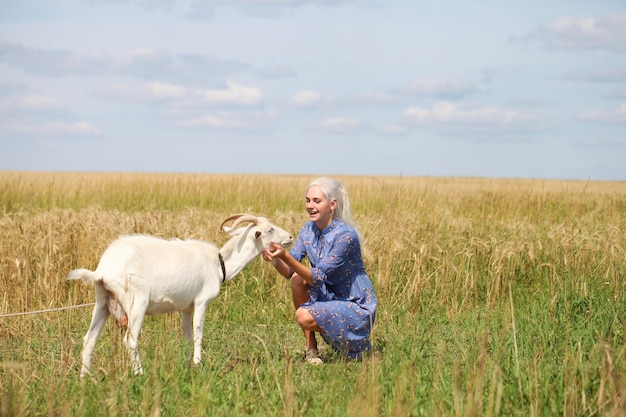 Retrato de uma jovem loira com uma cabra em um campo de trigo