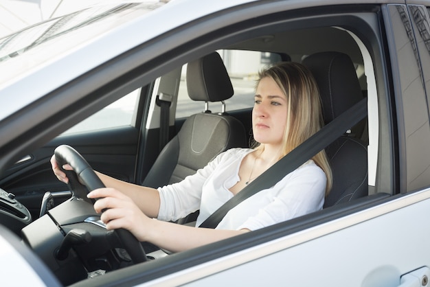 Retrato de uma jovem loira concentrada dirigindo um carro