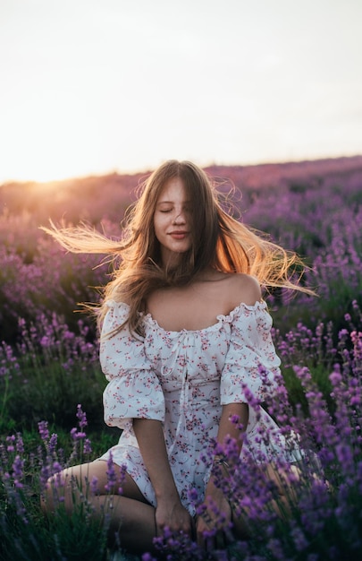 Retrato de uma jovem loira em um campo de lavanda no verão ao pôr do sol