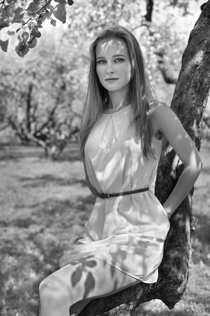 Retrato de uma jovem loira em um vestido azul. árvores em flores.