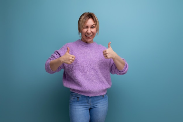 Retrato de uma jovem loira enérgica e brilhante com um suéter lavanda sorrindo para a câmera