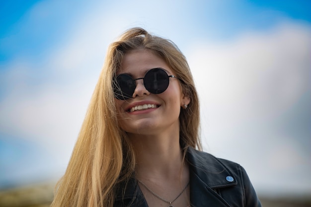 Retrato de uma jovem loira feliz em óculos de sol com cabelo comprido