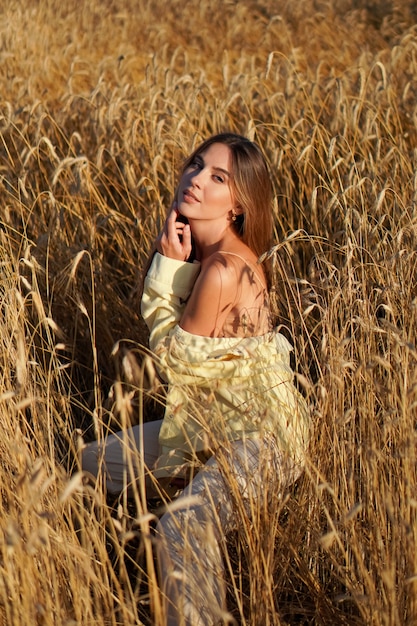 Retrato de uma jovem loira sorridente em um fundo de campo de trigo dourado