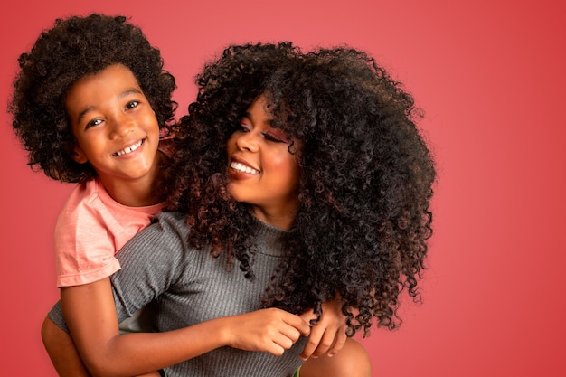 Foto retrato de uma jovem mãe afro-americana com o filho da criança. fundo vermelho. família brasileira.