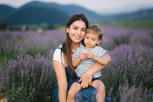 Retrato de uma jovem mãe atraente com filha pequena no campo de verão lavanda Família feliz no estilo jeans