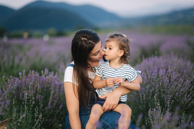 Retrato de uma jovem mãe atraente com filha pequena no campo de verão lavanda Família feliz no estilo jeans