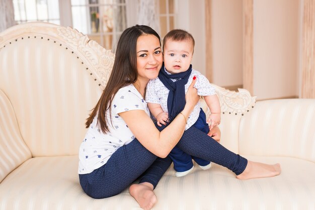 Retrato de uma jovem mãe com um bebê fofo em casa.