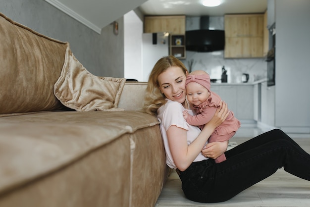 Retrato de uma jovem mãe com um bebê fofo em casa