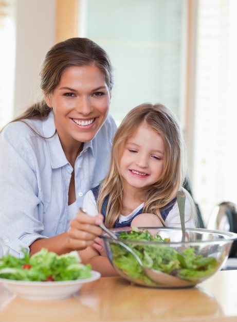 Retrato de uma jovem mãe e sua filha preparando uma salada