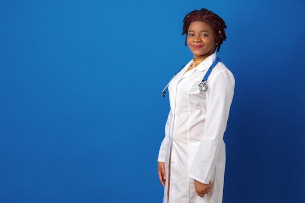 Retrato de uma jovem médica afro-americana contra uma superfície azul.