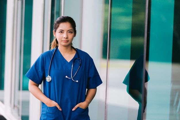 Retrato de uma jovem médica asiática do lado de fora do prédio do hospital com estetoscópio