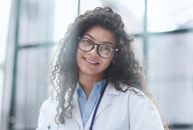 Retrato de uma jovem médica de jaleco branco no local de trabalho