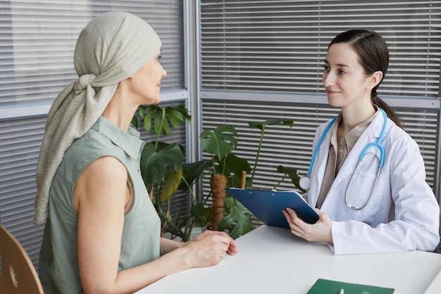 Retrato de uma jovem médica falando com o paciente durante a consulta na clínica médica, copie o espaço