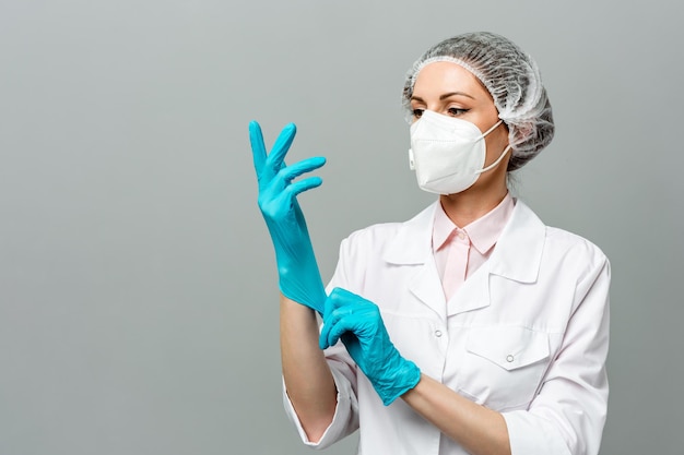 Retrato de uma jovem médica infeliz em uma máscara médica em um fundo cinza os médicos cansados