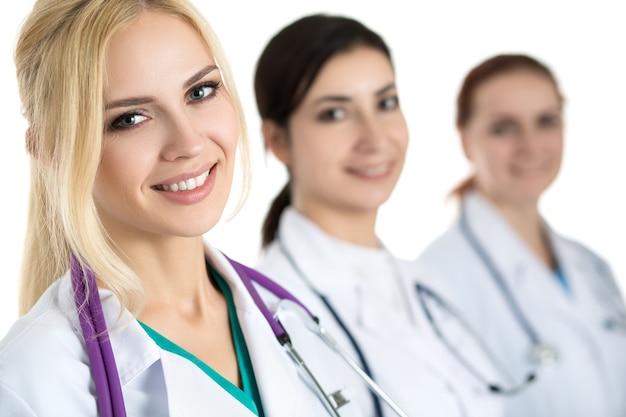 Retrato de uma jovem médica loira rodeada pela equipe médica, olhando e sorrindo. conceito de cuidados de saúde e medicina.