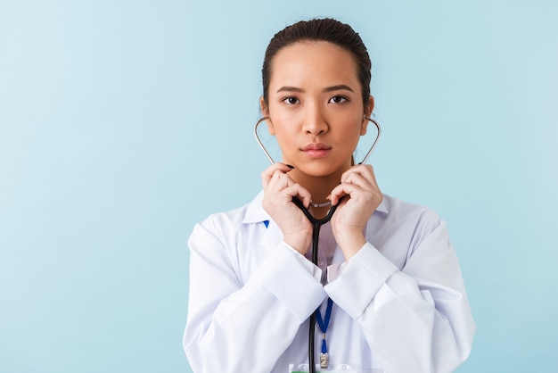 retrato de uma jovem médica posando isolado sobre uma parede azul com estetoscópio.