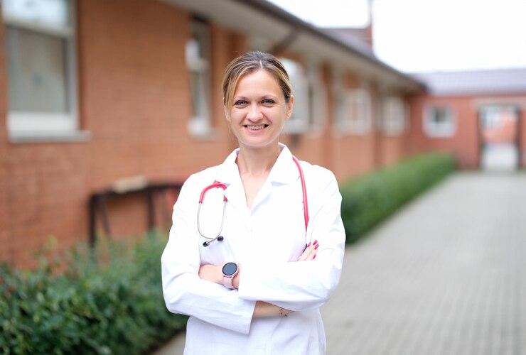 Foto retrato de uma jovem médica sorridente com um estetoscópio vermelho perto da clínica