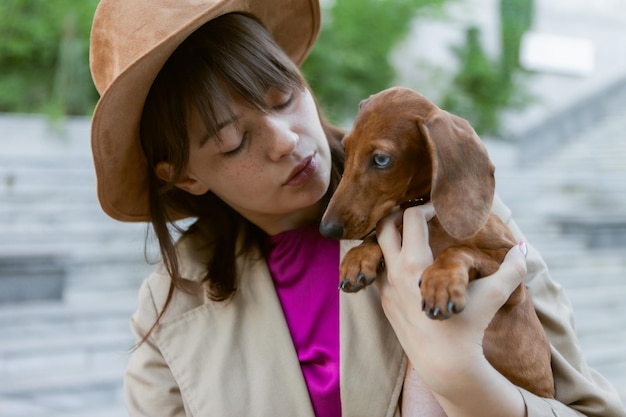 Retrato de uma jovem moda e um lindo filhote de dachshund em um parque da cidade. Amante e animal de estimação