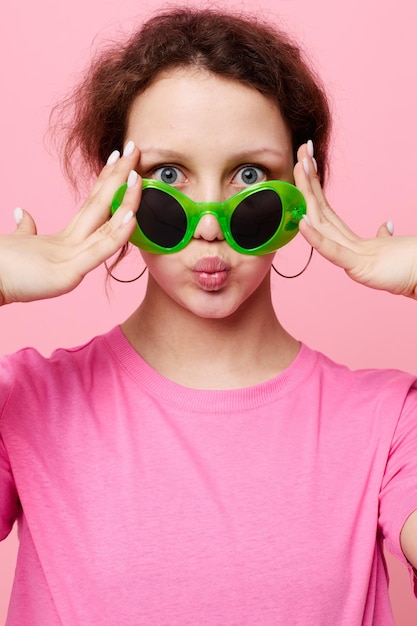 Retrato de uma jovem moda óculos verdes decoração de camiseta rosa posando