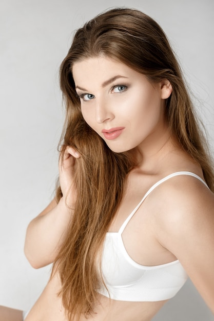 Retrato de uma jovem morena bonita com maquiagem natural em lingerie branca