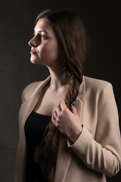 Retrato de uma jovem morena com cabelo comprido no estúdio Foto dramática em cores escuras