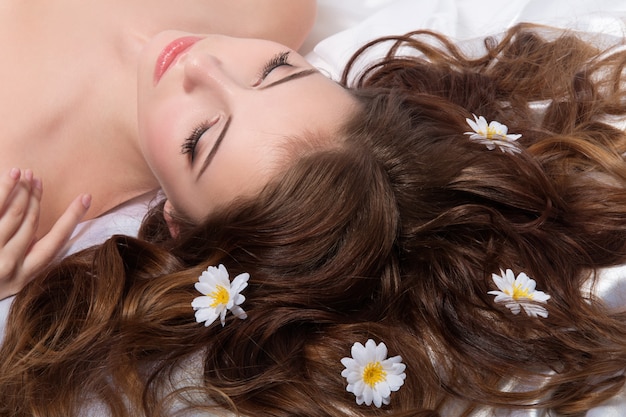Retrato de uma jovem morena com flores de camomila no cabelo