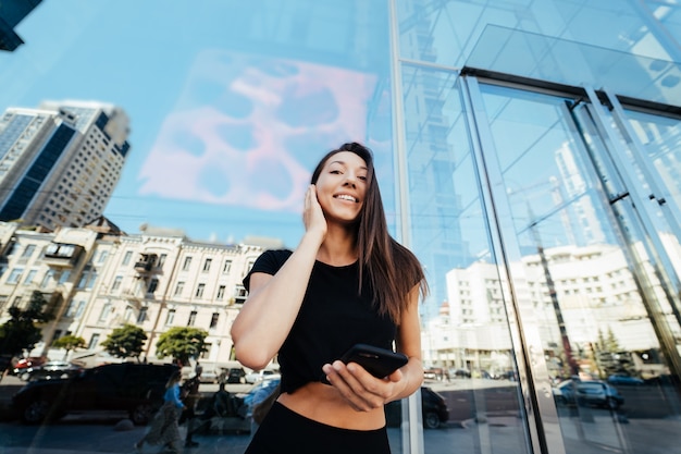 Foto retrato de uma jovem morena com fones de ouvido e sorrindo enquanto caminha