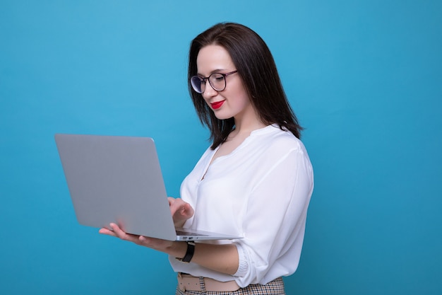 Retrato de uma jovem morena com um laptop em um fundo azul