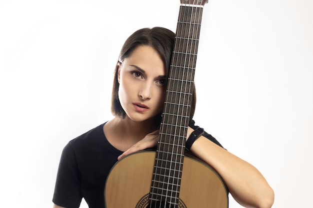 Foto retrato de uma jovem morena linda com violão clássico em fundo branco.