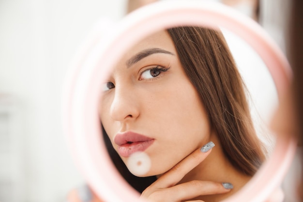 Retrato de uma jovem morena olhando no espelho o reflexo de uma mulher no espelho a garota admira seu reflexo no espelho