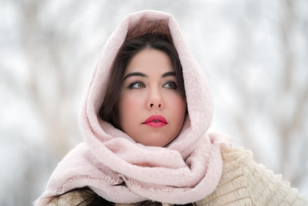 Retrato de uma jovem morena pensativa com casaco de pele branco e lenço rosa claro na cabeça olhando para longe