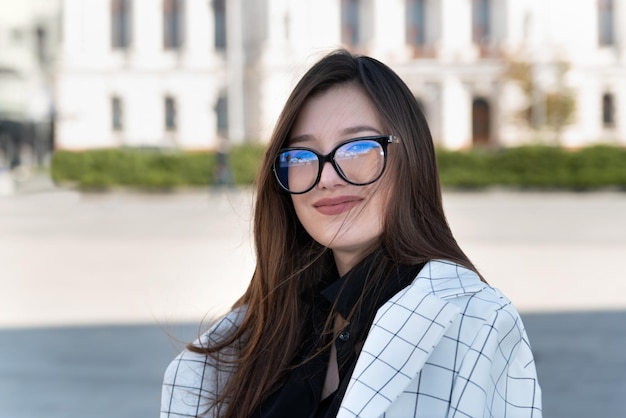 Retrato de uma jovem morena usando óculos Mulher de negócios contra o fundo da cidade