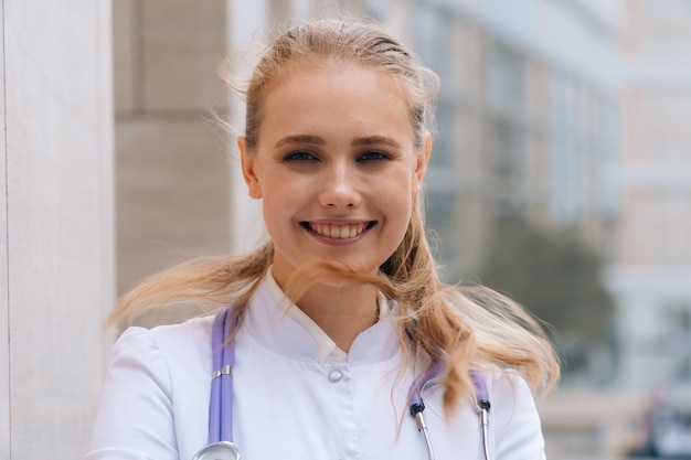 Retrato de uma jovem muito bonita com uma túnica branca. Close-up do rosto do médico sorridente feliz da mulher