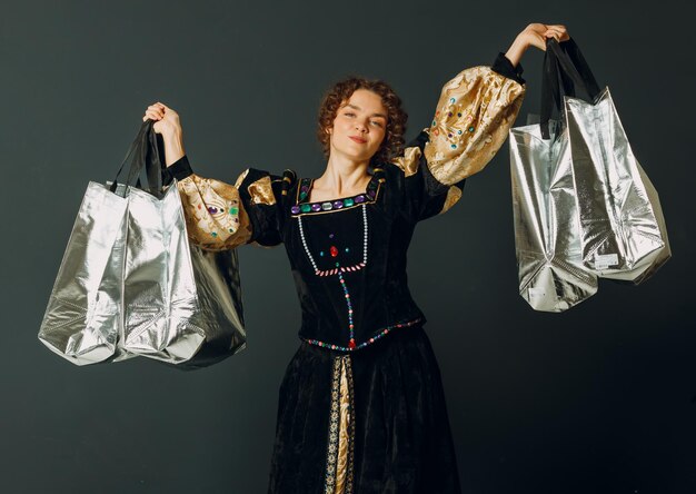 Retrato de uma jovem mulher adulta vestida com um vestido medieval segurando sacos de compras nas mãos