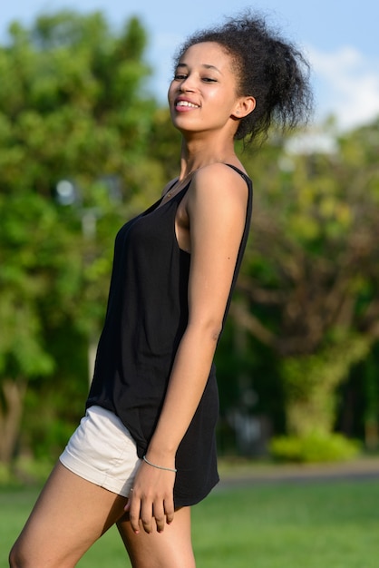 Retrato de uma jovem mulher africana bonita com cabelo afro relaxando no parque ao ar livre