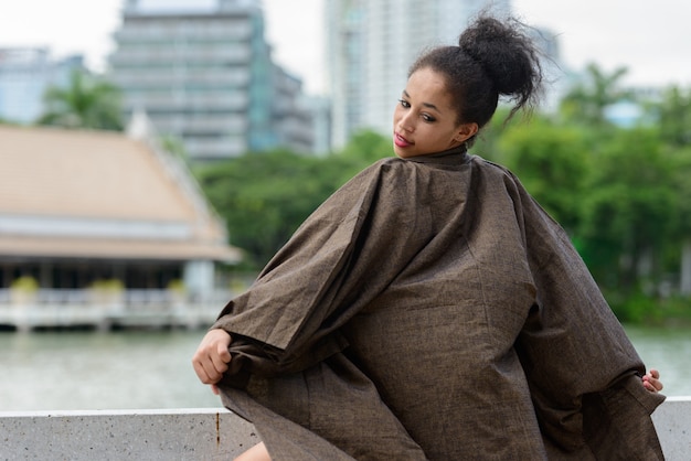 Retrato de uma jovem mulher africana bonita com cabelo afro relaxando no parque ao ar livre