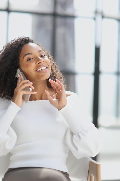 Retrato de uma jovem mulher afro-americana atraente usando um smartphone