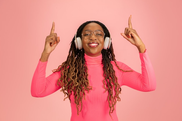 Retrato de uma jovem mulher afro-americana isolada no estúdio rosa, expressão facial.