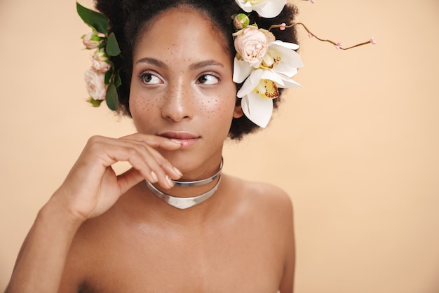 Retrato de uma jovem mulher afro-americana seminua e sardenta com flores no cabelo