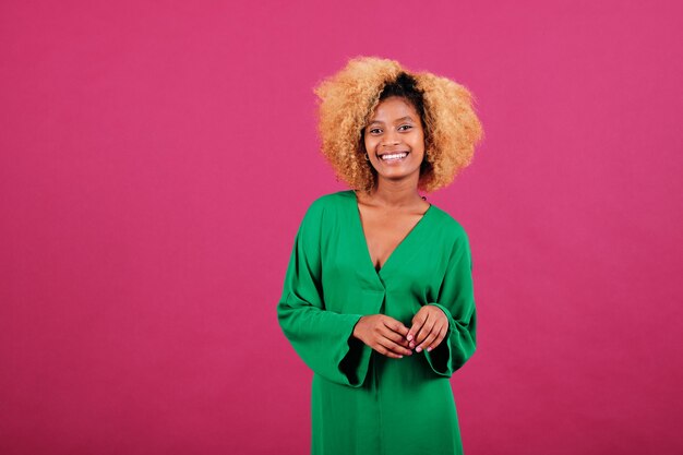 Retrato de uma jovem mulher afro com vestido verde, sorrindo em pé sobre um fundo isolado.