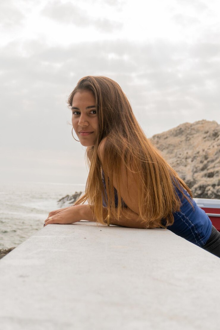 Foto retrato de uma jovem mulher apoiada em um corrimão na praia