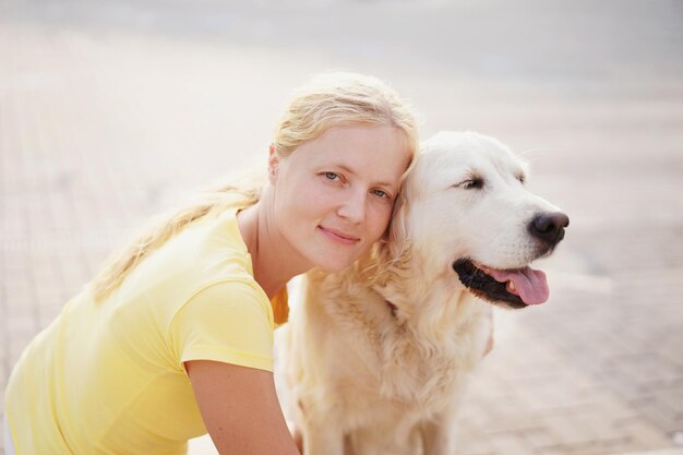 Retrato de uma jovem mulher apoiada em um labrador retriever durante um dia ensolarado