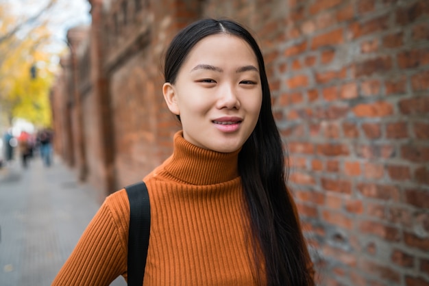 Retrato de uma jovem mulher asiática bonita em pé ao ar livre na rua. Conceito urbano.