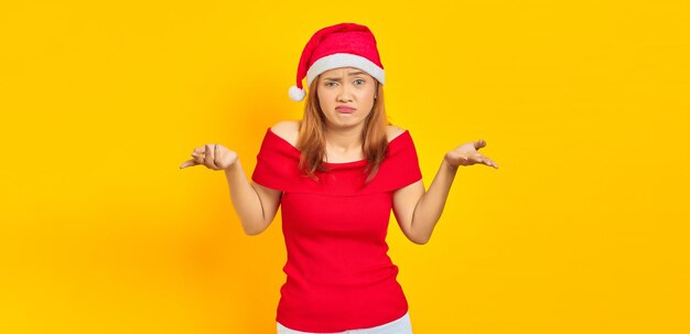 Retrato de uma jovem mulher asiática com chapéu de Natal tendo dúvidas e expressão facial confusa