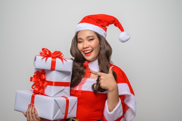 Retrato de uma jovem mulher asiática com fantasia de Papai Noel vermelho, sorrindo e segurando uma caixa de presente.
